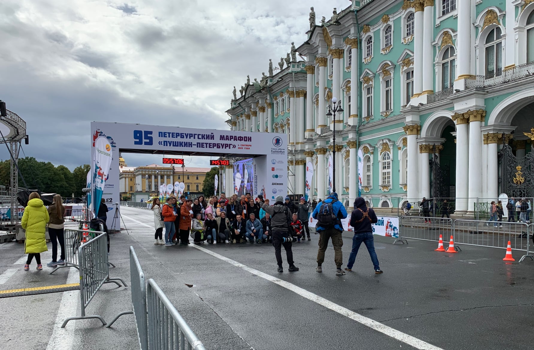 Группа людей фотографируется на фоне финишной арки марафона в Санкт-Петербурге
